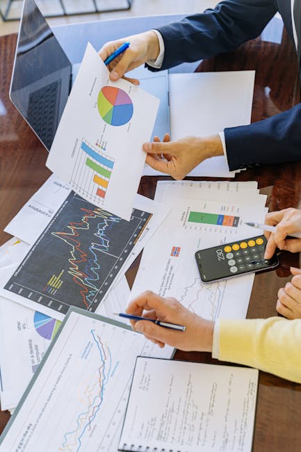 Des professionnels d'entreprise analysant des graphiques et tableaux financiers pendant une réunion.