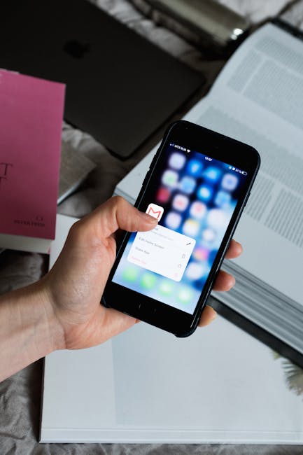 Main utilisant un smartphone avec une appli Gmail ouvert.